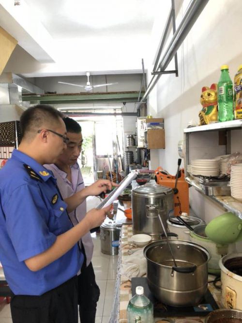 綜合執(zhí)法人員對餐飲企業(yè)進(jìn)行油煙污染檢查