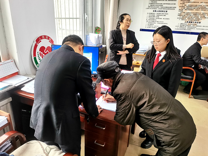 當(dāng)事人秦某（左二）在調(diào)解員張海川（左一）及工作人員的指導(dǎo)下,，寫下確認(rèn)收到賠償?shù)恼f(shuō)明