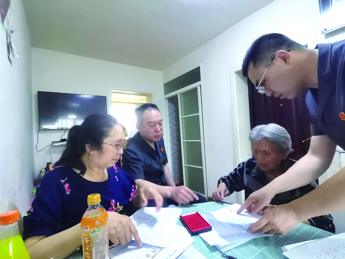 付承志（右一）胡善福（左二）指導(dǎo)潘某榮（右二）在調(diào)解書上簽字,、按手印