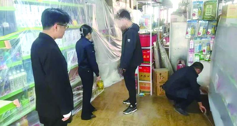 二圖,，法院干警正在幫助一樓商戶粘貼防塵塑料布