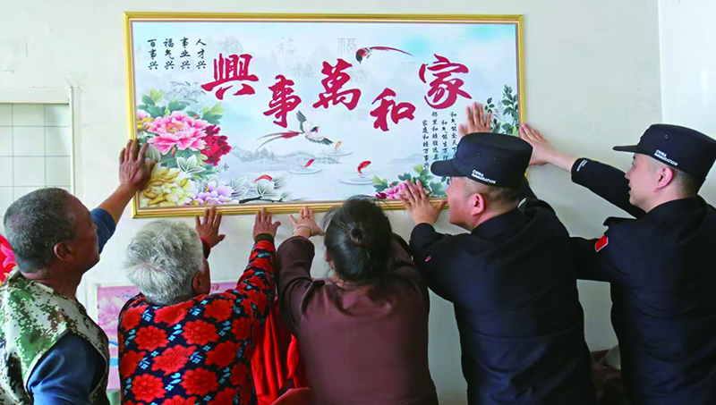 二題圖，民警和這一家人一起把“家和萬(wàn)事興”掛畫貼上墻